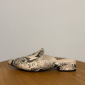 Cole Haan Piper mules with a snakeskin print leather upper.